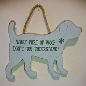 A dog shaped wooden sign with the words "What part of woof don't you understand?" in capitals